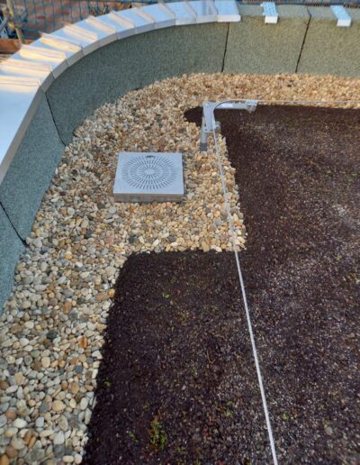 Dachbegrünungen, Kies und Erde um einen Abfluss